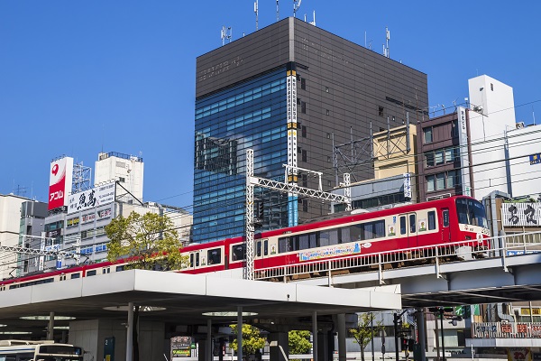 「川崎」駅東口の高架線路を走る京浜急行線の赤い車両